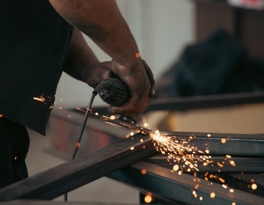 Travaux de métallerie sur mesure – AC2A Aubance Artisan métallier en train de meuler une structure en acier, fabrication sur mesure par AC2A Aubance.